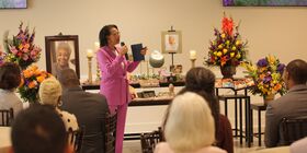 Seated guests listen to a celebrant speak at a funeral reception