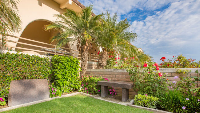 Large, private garden with tropical landscaping and a bench at Pacific View Memorial Park.