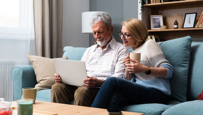 Senior couple looking at a computer at home on their couch