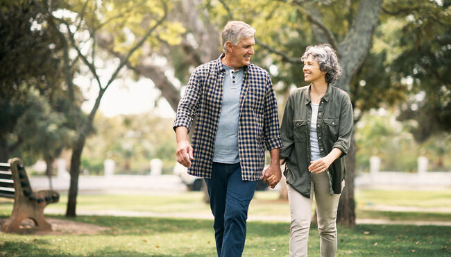 couple holding hands and smiling to each other while walking in the park