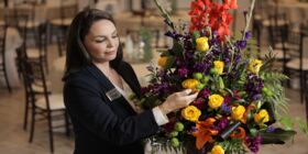 A female Dignity Memorial associate adjusts a floral arrangement in preparation for a celebration of life