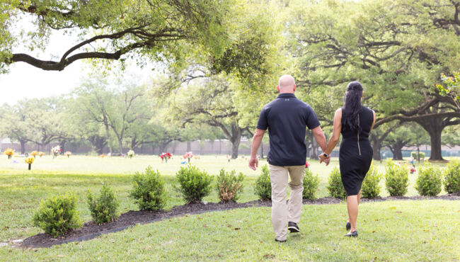 Couple holding hands walking on cemetery grounds