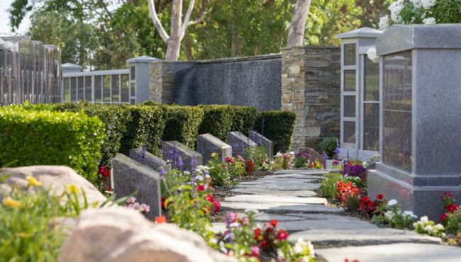 Scenic pathway in the Cremation Garden with flowers, green grass, and trees.