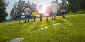 Three generations of a family walk toward the sun on a visit to their place of remembrance.  