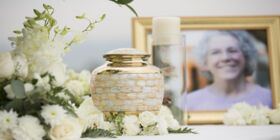 An Urn sits near white roses and a portrait.